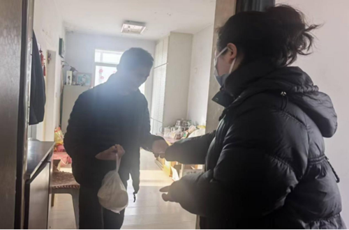 图为社区工作人员帮助残疾人购买早餐